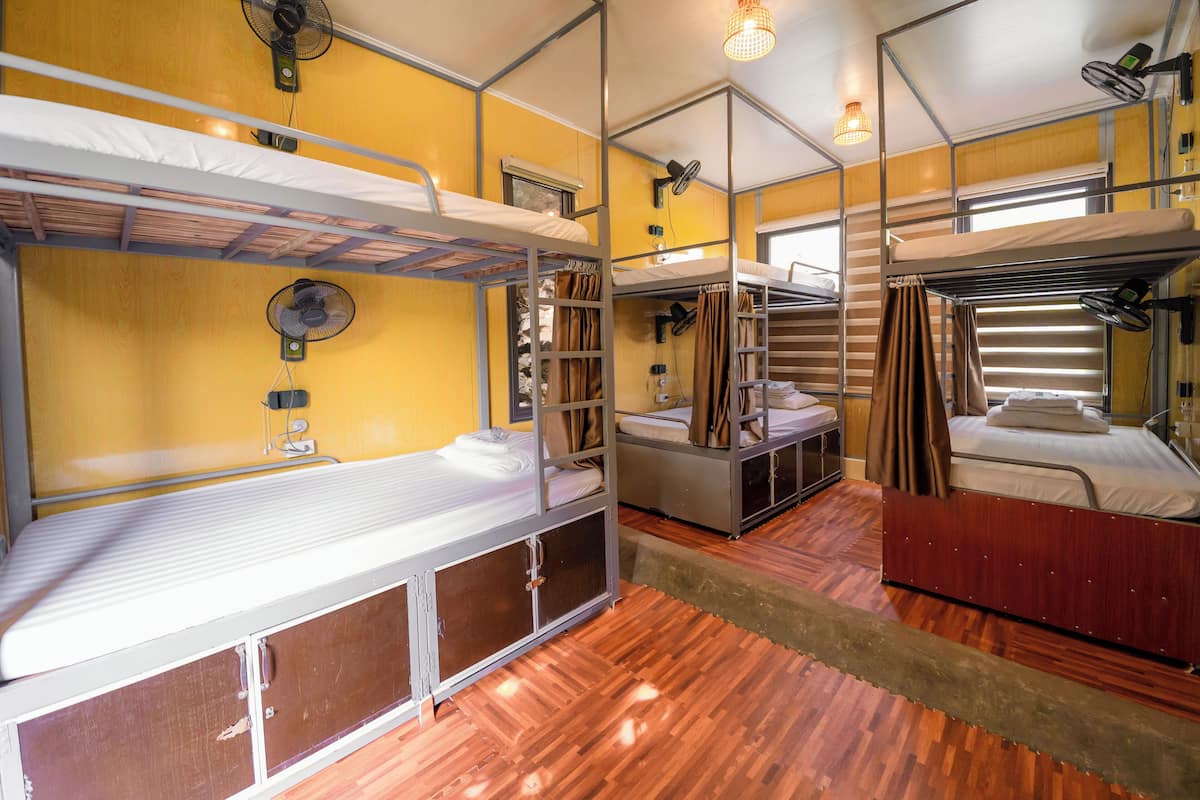 A compact room with bunk beds, wooden flooring, and a small window.