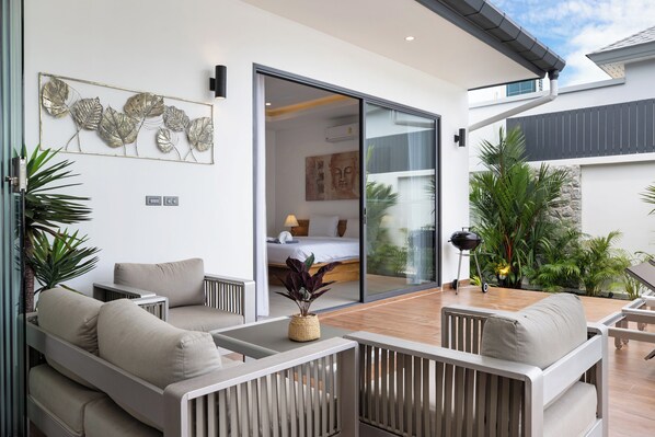 A modern outdoor living area with a sofa, a dining table, and a grill. - Two-Bedroom Villa with Salt Pool in Rawai (rawai)