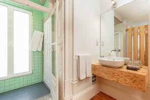 A bathroom with a large mirror, a wooden vanity, and a green-tiled shower area. - Modern Porto studio with essential amenities (Oporto)