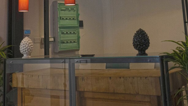 L’extérieur de l’auberge Vucciria Ostello se distingue par son enseigne lumineuse, ses lampes suspendues et son entrée en verre.