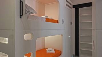 A bunk bed with a white headboard and orange bedding, a white wall with a handle, and a white door with a black frame.