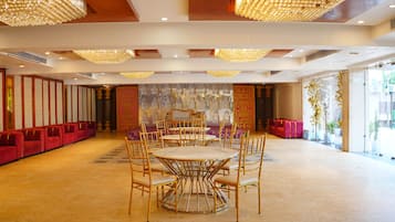 A spacious room with a large round table and chairs, a seating area with red sofas, and a decorative wall with intricate patterns.