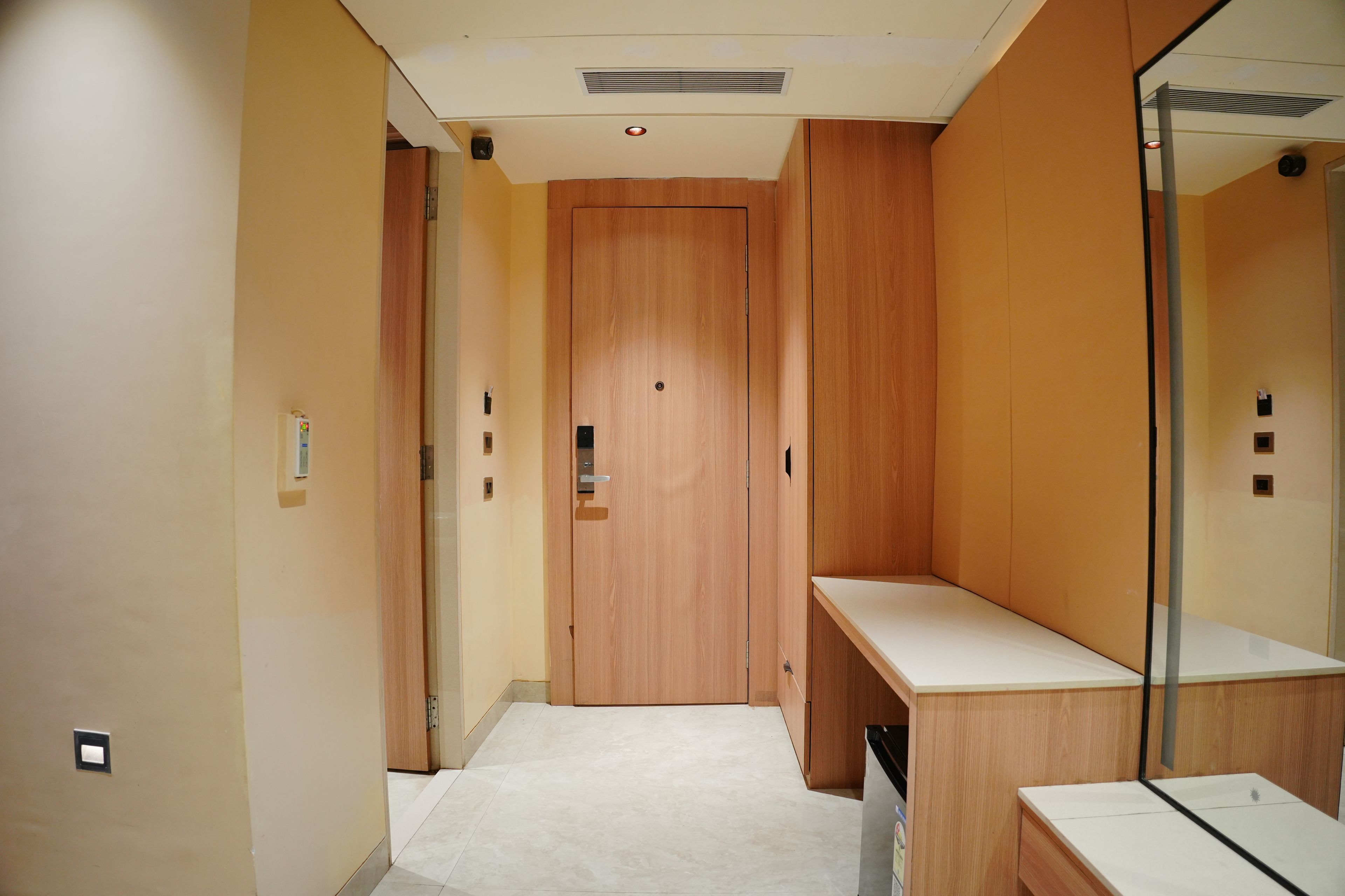 A hallway with a wooden door, a mirror, and a white countertop.