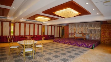 Ein Zimmer mit einem runden Tisch, Stühlen, einer Couch und einer Bühne mit einem gemusterten Teppich.