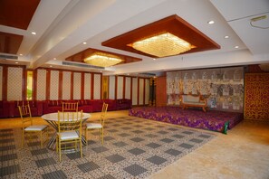 Une pièce comprenant une table ronde, des chaises, un canapé et une scène recouverte d’un tapis à motifs.