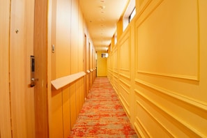 A hotel corridor with wooden doors, a patterned carpet, and a yellow wall. - The Grand Sun City Hotel & Resort (Bhopal)
