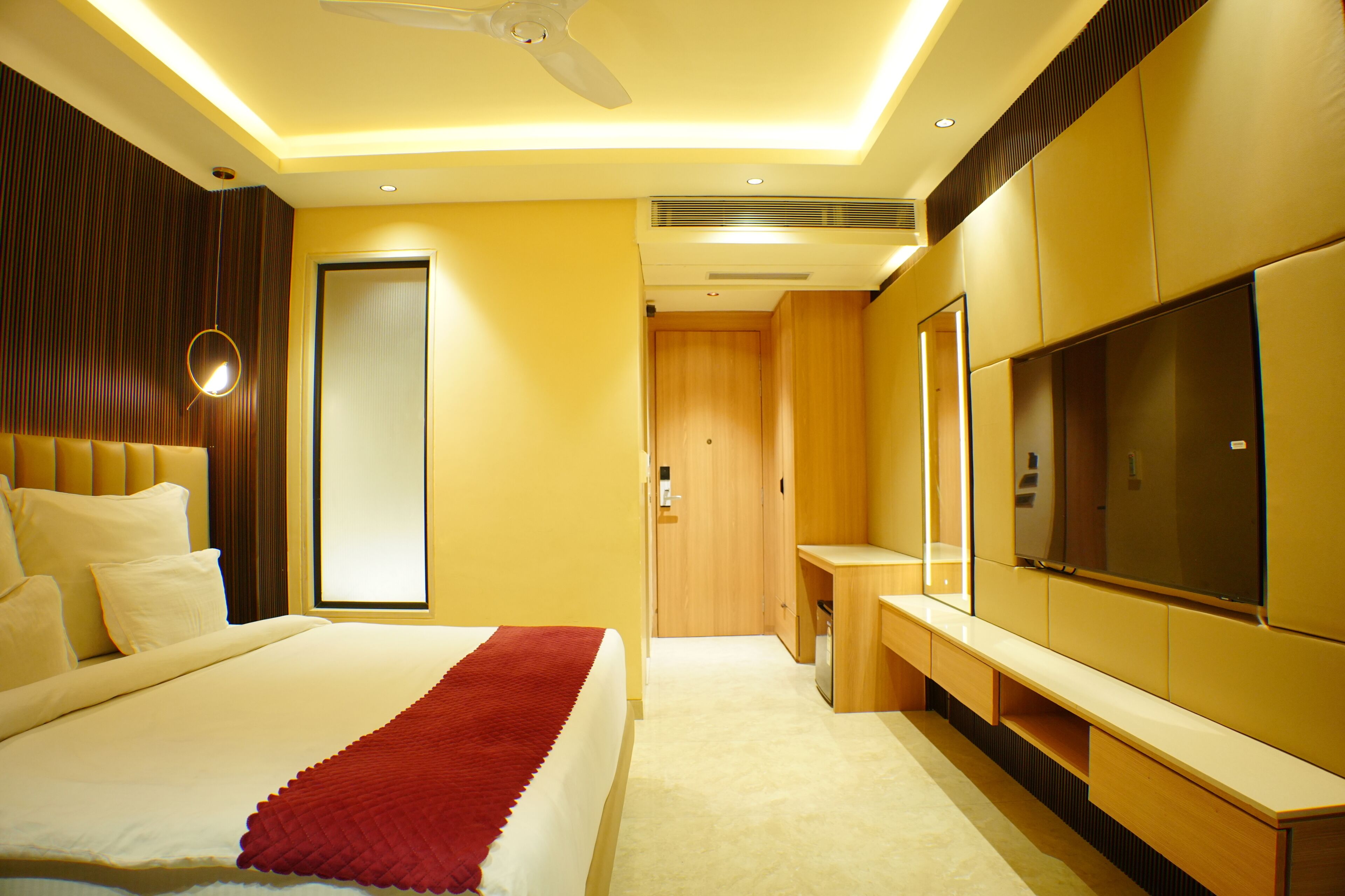 A modern hotel room with a large bed, a flat-screen TV, and a wooden wardrobe.