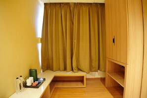 A small room with a wooden cabinet, a bench, and a tray with bottles and cups.