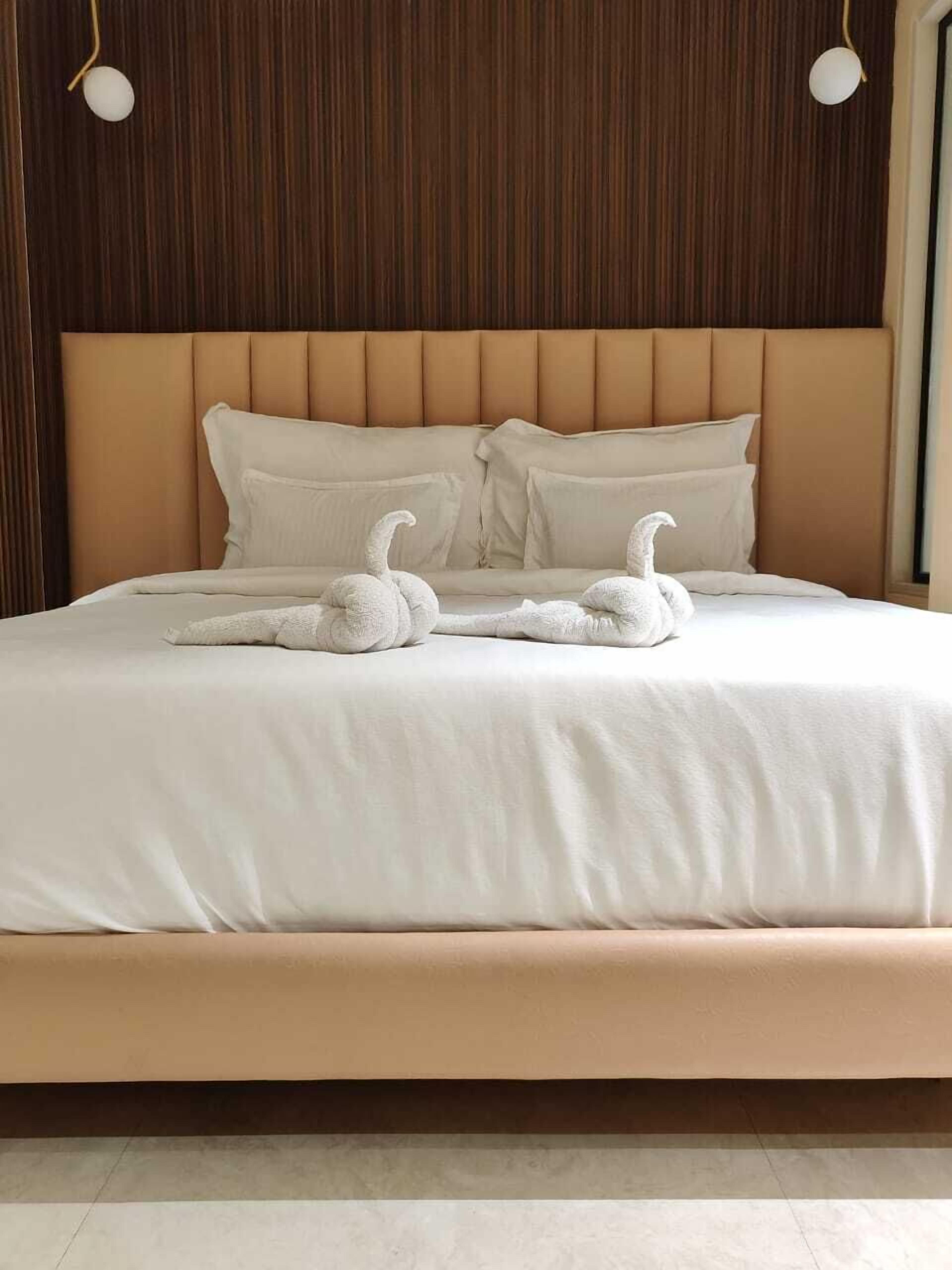 A bed with a headboard, pillows, and two swan-shaped decorations.