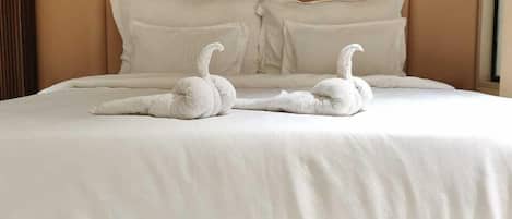 A bed with a headboard, pillows, and two swan-shaped decorations.