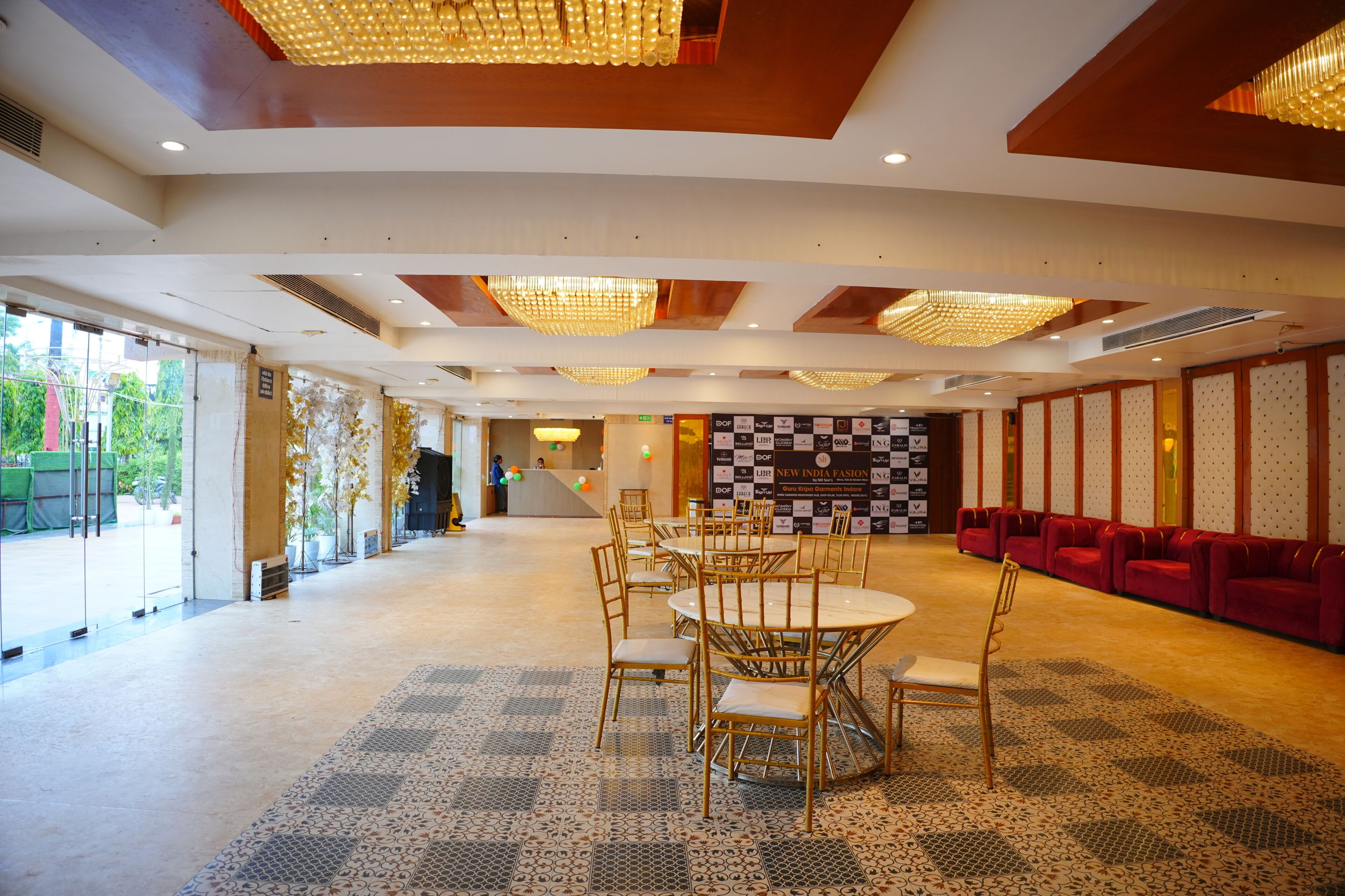 A spacious hall with a checkered floor pattern, a reception desk, and a row of red sofas.