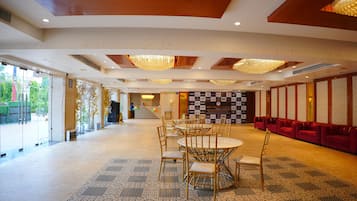 A spacious hall with a checkered floor pattern, a reception desk, and a row of red sofas.