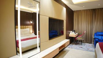 A modern hotel room with a bed, a TV, a desk, and a chair.