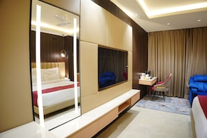 Ein modernes Hotelzimmer mit einem Bett, einem Fernseher, einem Schreibtisch und einem Sessel.
