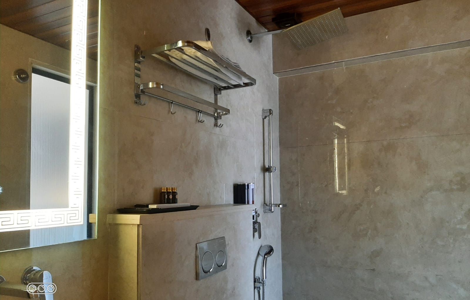 A modern bathroom with a large mirror, a towel rack, a shower, and a sink.
