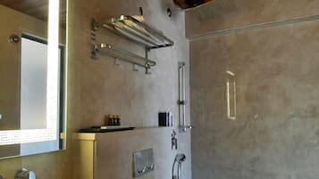 A modern bathroom with a large mirror, a towel rack, a shower, and a sink.