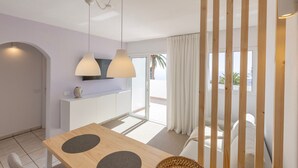 Una sala moderna con una mesa de comedor de madera, un sofá y un televisor montado en la pared.