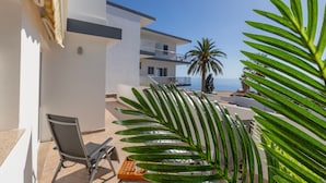 Un edificio moderno con un balcón, una silla y una palmera.