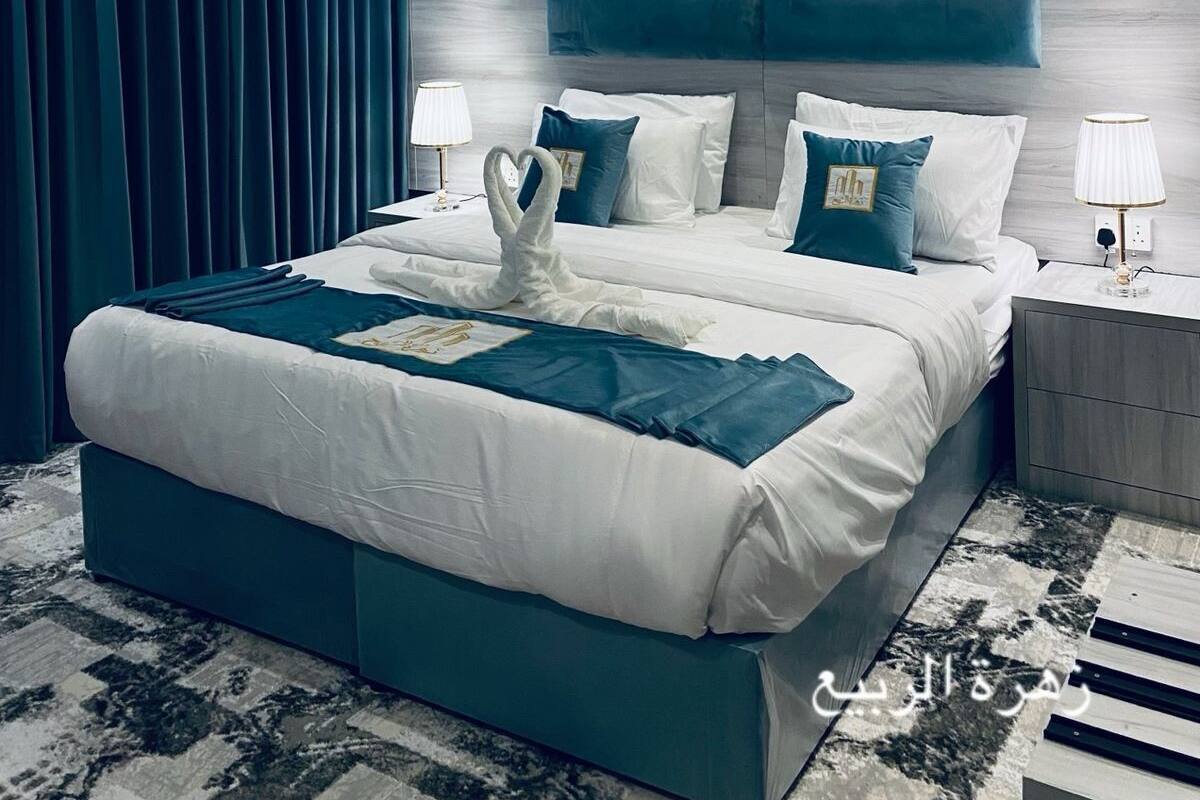 A modern hotel room with a large bed, a headboard with a feather artwork, and a view of the city.