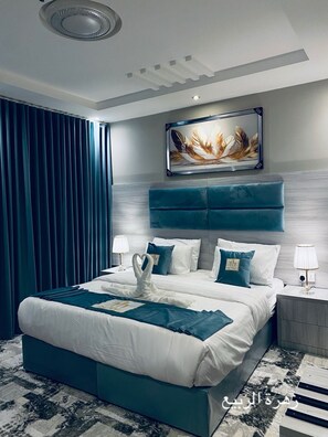 A modern hotel room with a large bed, a headboard with a feather artwork, and a view of the city. - zahrat alrabie lilshuqaq almakhduma (Jeddah)
