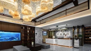 A modern hotel lobby with a reception desk, a large flat-screen TV, and a decorative ceiling. - ZEHAI HOTEL (Xi'an)
