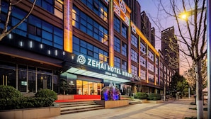 A hotel with a modern facade, large windows, and a prominent entrance with a red carpet. - ZEHAI HOTEL (Xi'an)