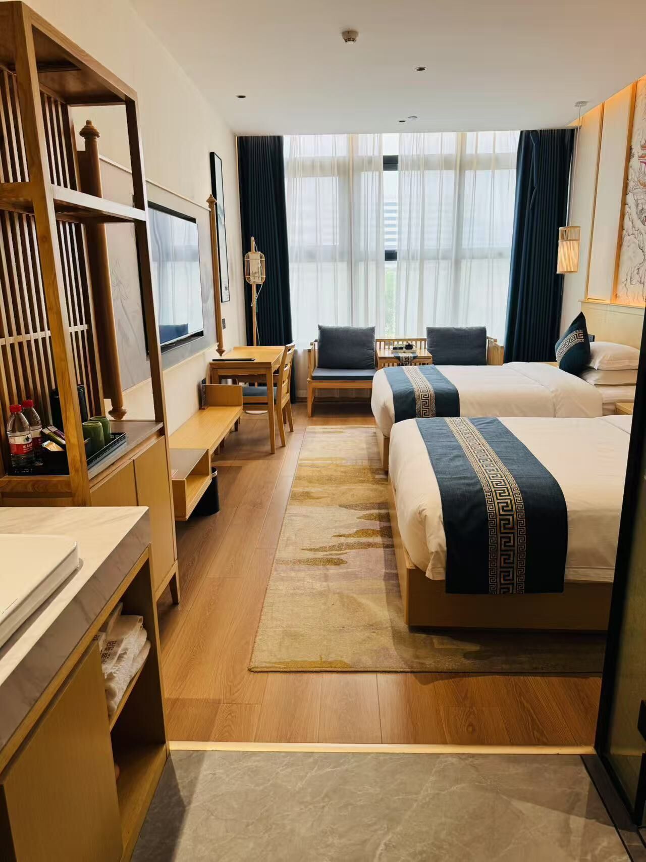 A hotel room with a large bed, a desk, a chair, and a sofa.