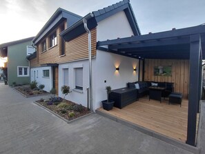 A modern house with a patio, wooden deck, and outdoor seating area. - Chalet 'Pauline' with Shared Terrace, Shared Garden and Wi-Fi (Breitengüßbach)