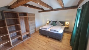 Ein Schlafzimmer mit einem Bett, Holzböden, einem Nachttisch und einer Decke mit freiliegenden Balken.