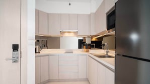 Une cuisine moderne avec des meubles en bois clair, des appareils en acier inoxydable et un four à micro-ondes encastré.