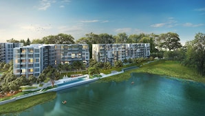 Un complexe d’appartements moderne composé de plusieurs bâtiments, doté d’un élément aquatique central et entouré de verdure.