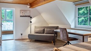 A room with a sloped ceiling, a sofa, a desk, and a chair. - Apartment 'Landlust' with Shared Terrace, Shared Garden and Wi-Fi (Neudrossenfeld)