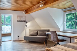 A room with a sloped ceiling, a sofa, a desk, and a chair.