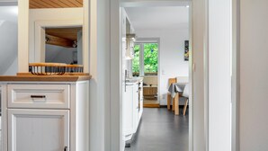 A modern kitchen with white cabinets, a wooden countertop, and a view into the dining area. - Apartment 'Landlust' with Shared Terrace, Shared Garden and Wi-Fi (Neudrossenfeld)