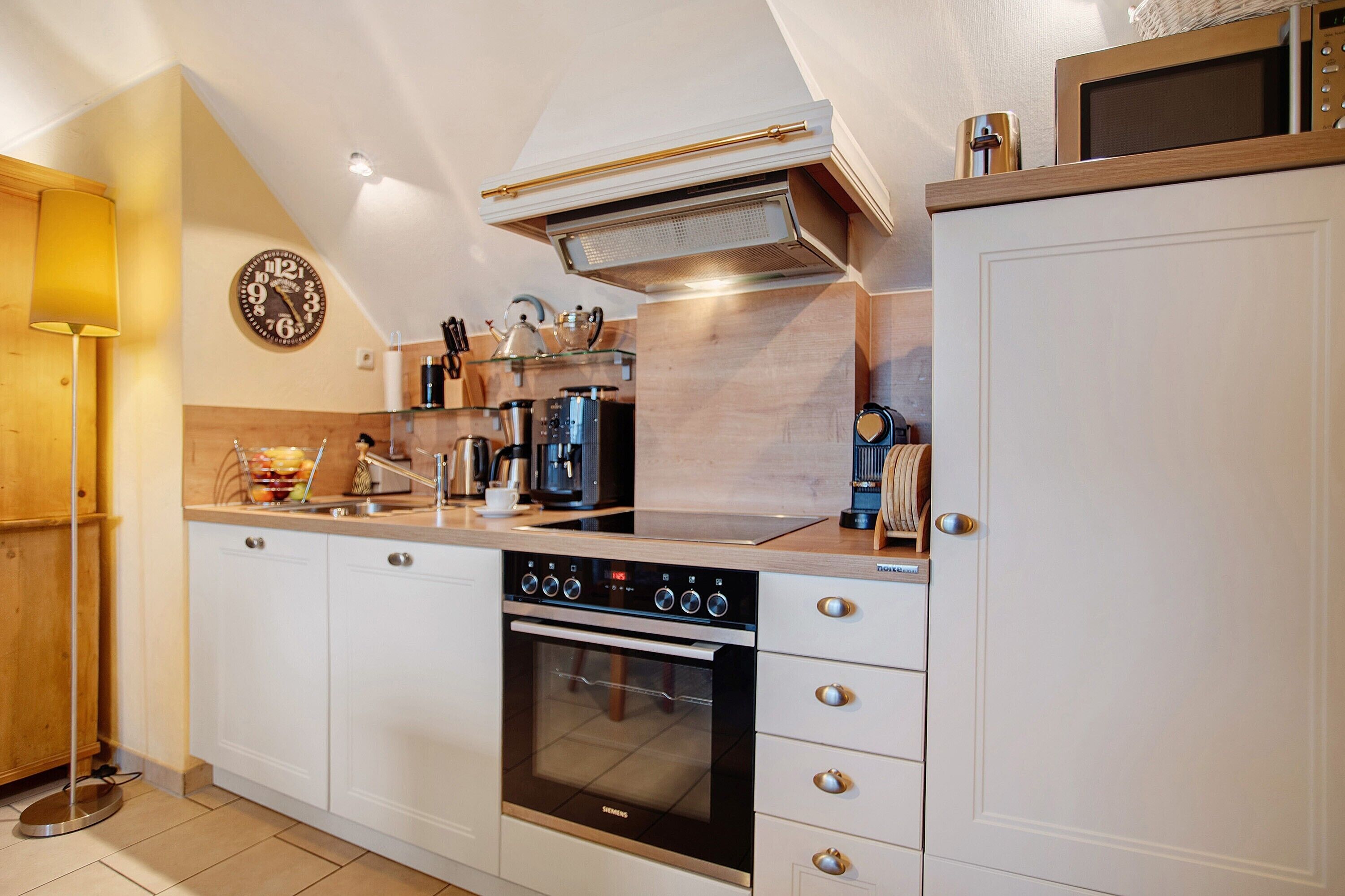 A modern kitchen with a built-in oven, microwave, and coffee maker.