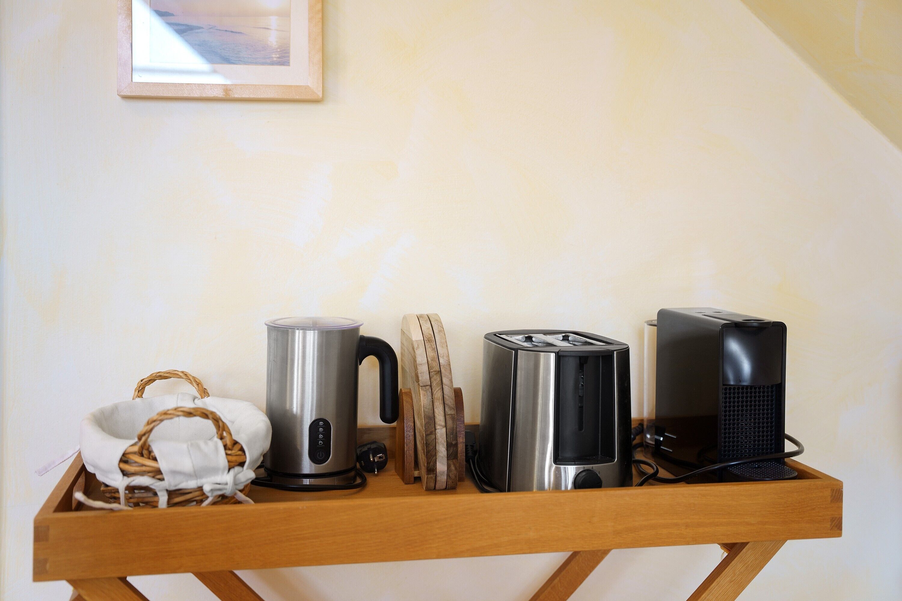 Una encimera de cocina con una tetera, un tostador y un altavoz.