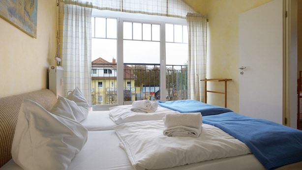 Une chambre d’hôtel avec deux lits, une vue par une grande fenêtre, un radiateur et un tableau au mur.