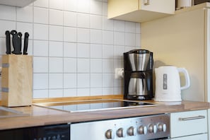 Una cocina con cafetera, tostadora y bloque de cuchillos.