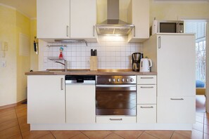 A kitchen with a dishwasher, oven, microwave, and a coffee maker.