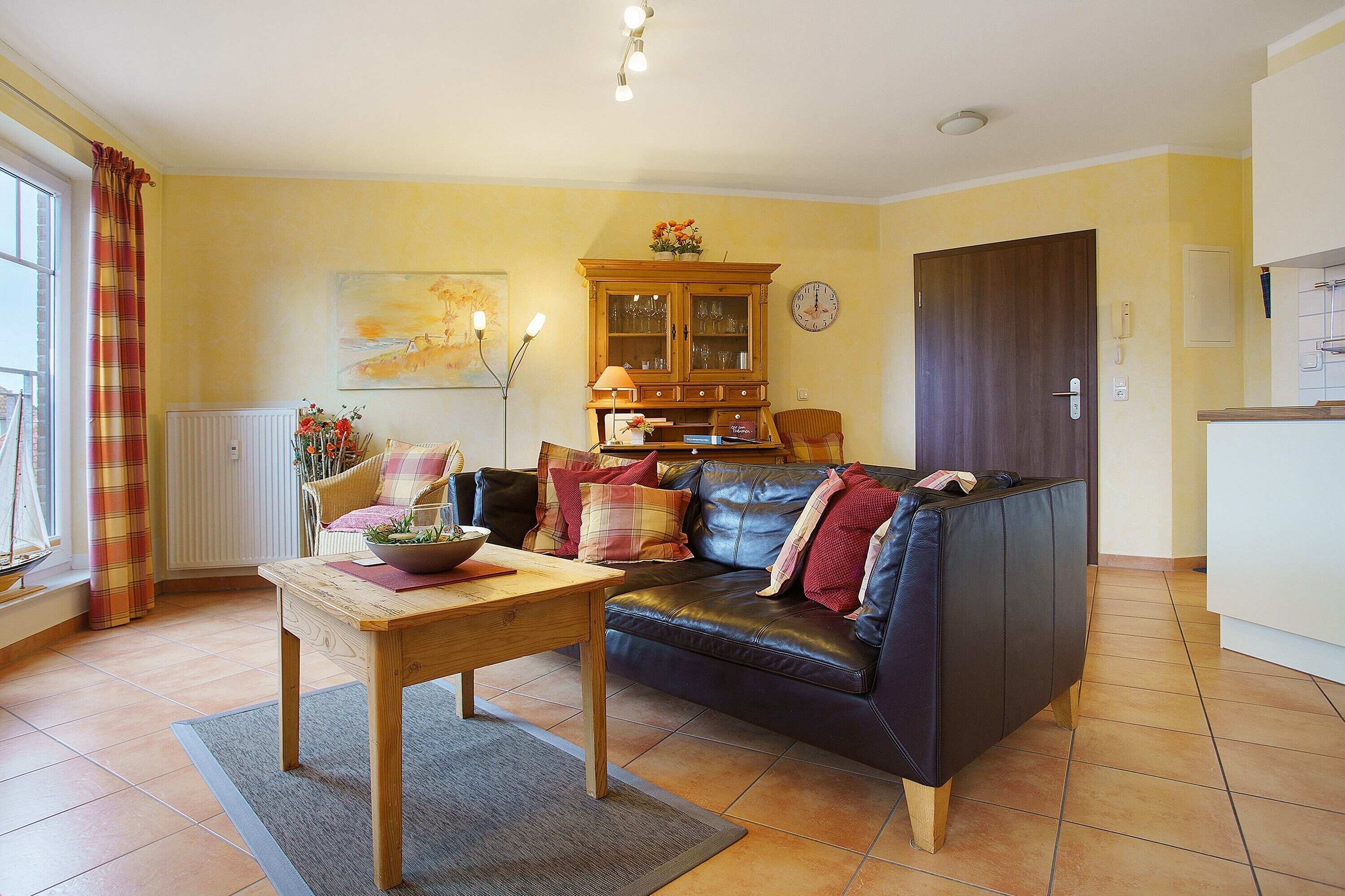 A living room with a sofa, a wooden table, a cabinet, and a window with curtains.