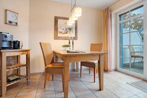 Un'area pranzo con un tavolo di legno, sedie, una macchina per il caffè, un'opera d'arte incorniciata e una finestra con tende.