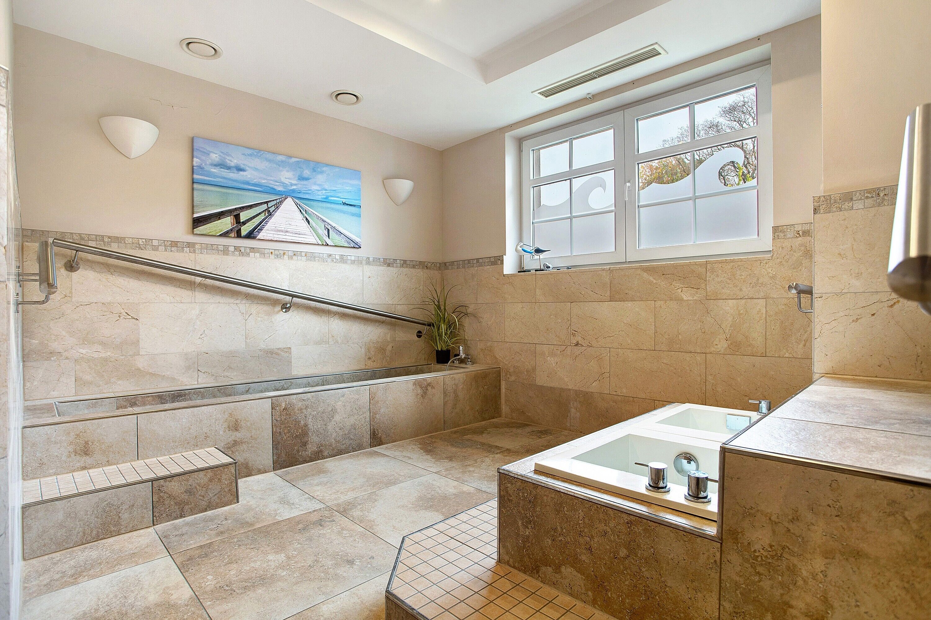 Ein Badezimmer mit einer Badewanne, einer Dusche, einem Fenster und einem Bild an der Wand.
