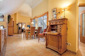 A spacious kitchen with wooden cabinets, a dining area with chairs, and a large window with curtains. - Wellness & Living Under Thatch: Apartment 18 'Wellness Residence' (Zingst)