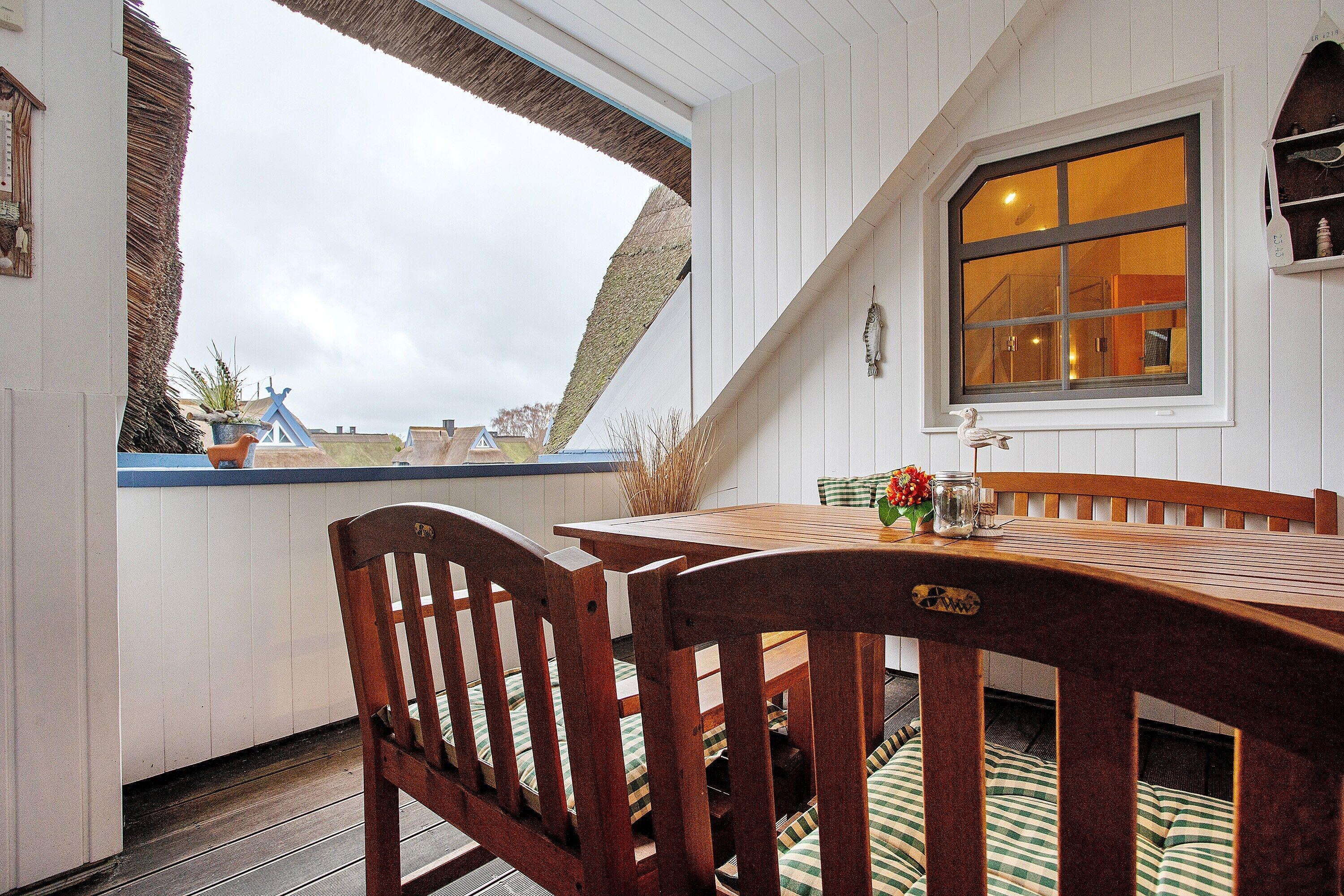 Ein Holztisch mit Stühlen, ein Fenster und Blick zum Himmel.
