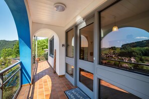 A balcony with a view of a village, a door with a glass panel, and a doormat with text.