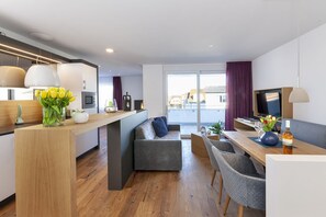 Een moderne woonruimte met keuken, eethoek en zithoek.