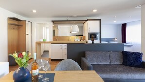 Een moderne hotelkamer met een eethoek, kitchenette en een bank met decoratief kussen.