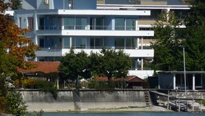 Een modern meerlaags gebouw met grote ramen, een plat dak en uitzicht op het water.