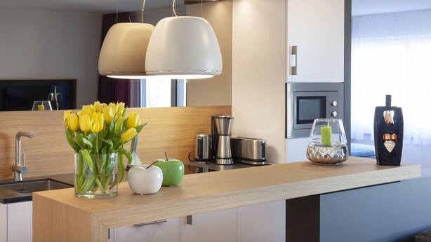 Een moderne keuken met een houten aanrecht, een koffiezetapparaat, een broodrooster en een vaas met gele tulpen.