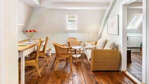 A cozy room with a dining table, wicker chairs, a sofa, and a small window. - Holiday Apartment in the Former Manor 'Bergblick' with Garden and Wi-Fi (Wurzbach)